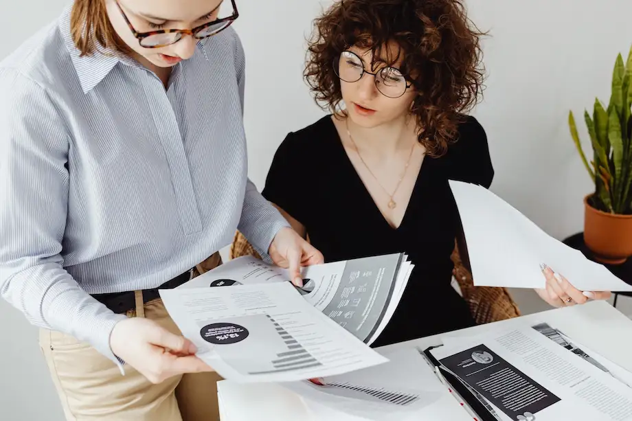 Business women at desk looking at papers with charts